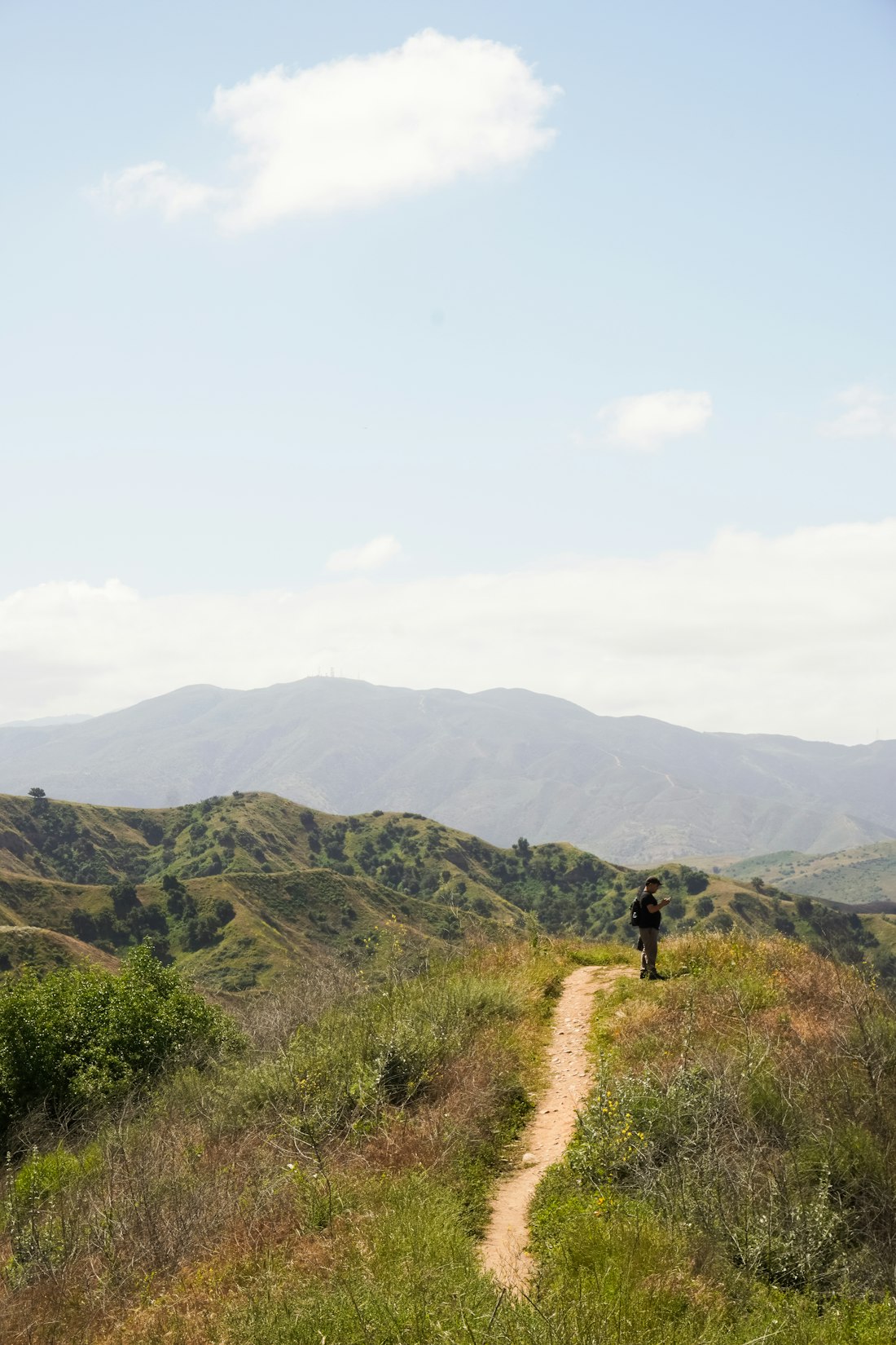 A hiker pausing on a ridge trail above the ocean